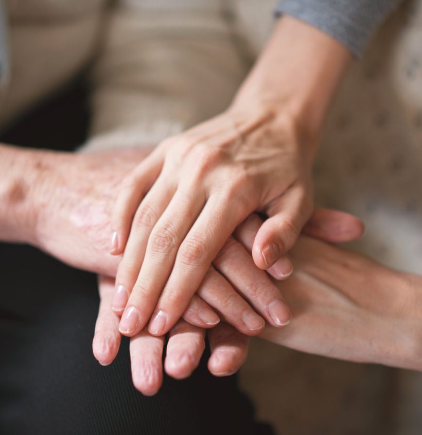 Elderly woman holding hands with daughter.